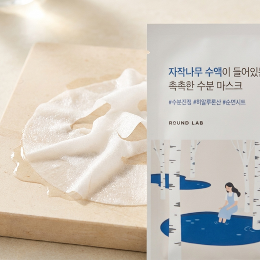 Nasses Tuch der Round Lab Birch Juice Maske auf hellem Stein, Sachet angeschnitten daneben