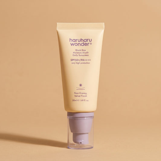 Haruharu Wonder Black Rice Airy-fit Sunscreen SPF 50+, 50 ml Tube auf sandfarbenem Hintergrund
