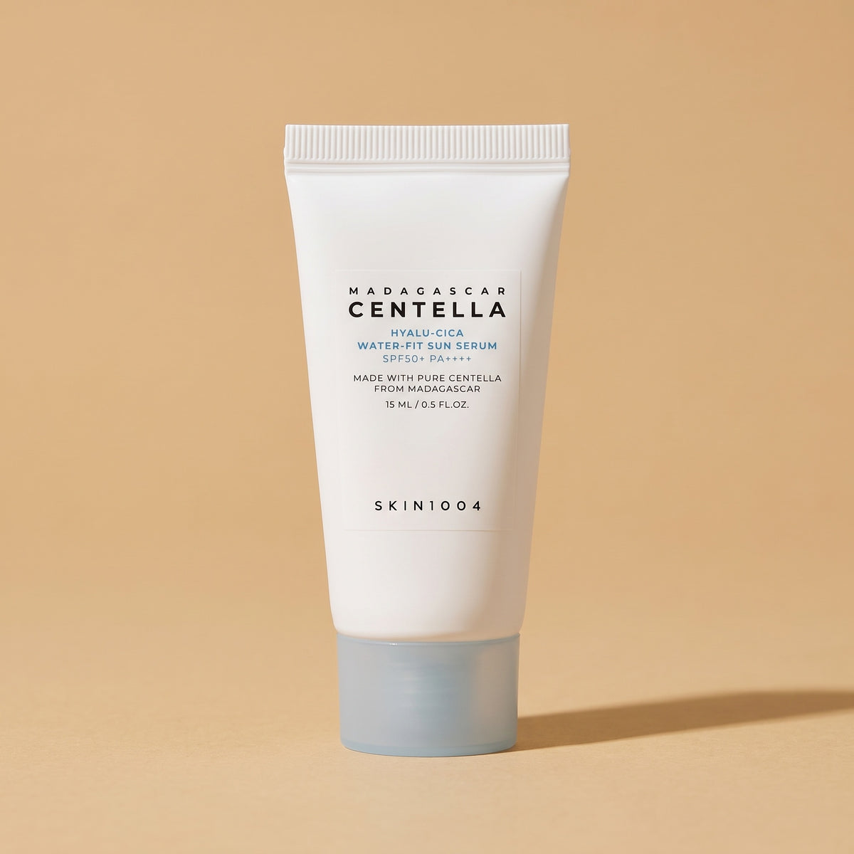 SKIN1004 Madagascar Centella Hyalu-Cica Water-Fit Sun Serum SPF 50+, 15 ml Tube auf sandfarbenem Hintergrund