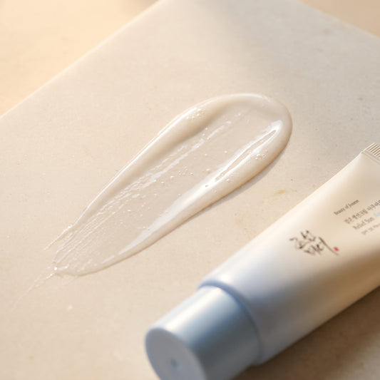 Cremetextur der Beauty of Joseon Relief Sun Aqua-Fresh auf hellem Stein, die Tube liegt angeschnitten daneben