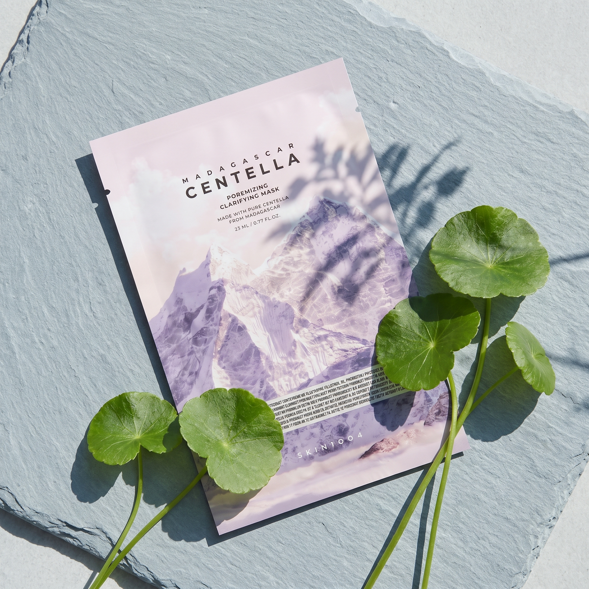 SKIN1004 Poremizing Clarifying Mask liegt auf kühlem grauem Schiefer, daneben Centella-Blätter