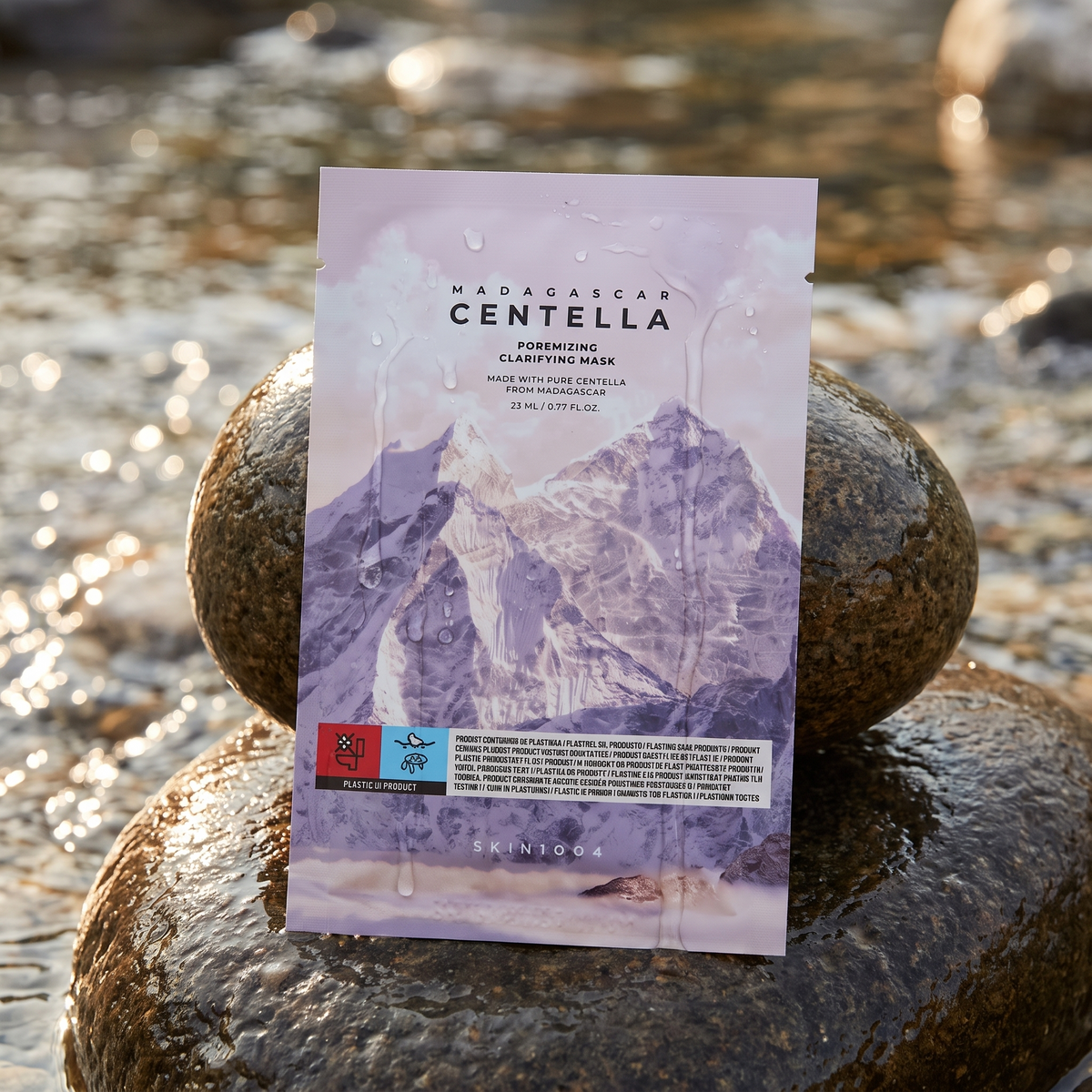 SKIN1004 Poremizing Clarifying Mask lehnt an einem nassen Stein am Bach, Wassertropfen auf der Folie