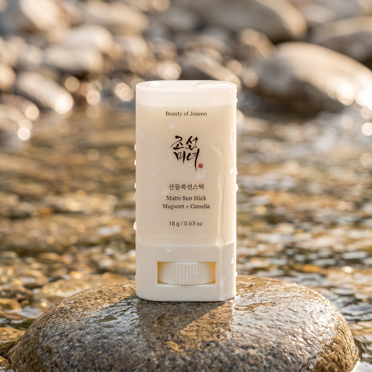 Beauty of Joseon Matte Sun Stick steht auf einem nassen Stein am Bach, Wassertropfen auf dem Stick